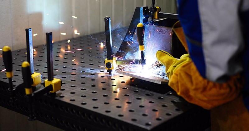 man welds at the factory working in metal industry