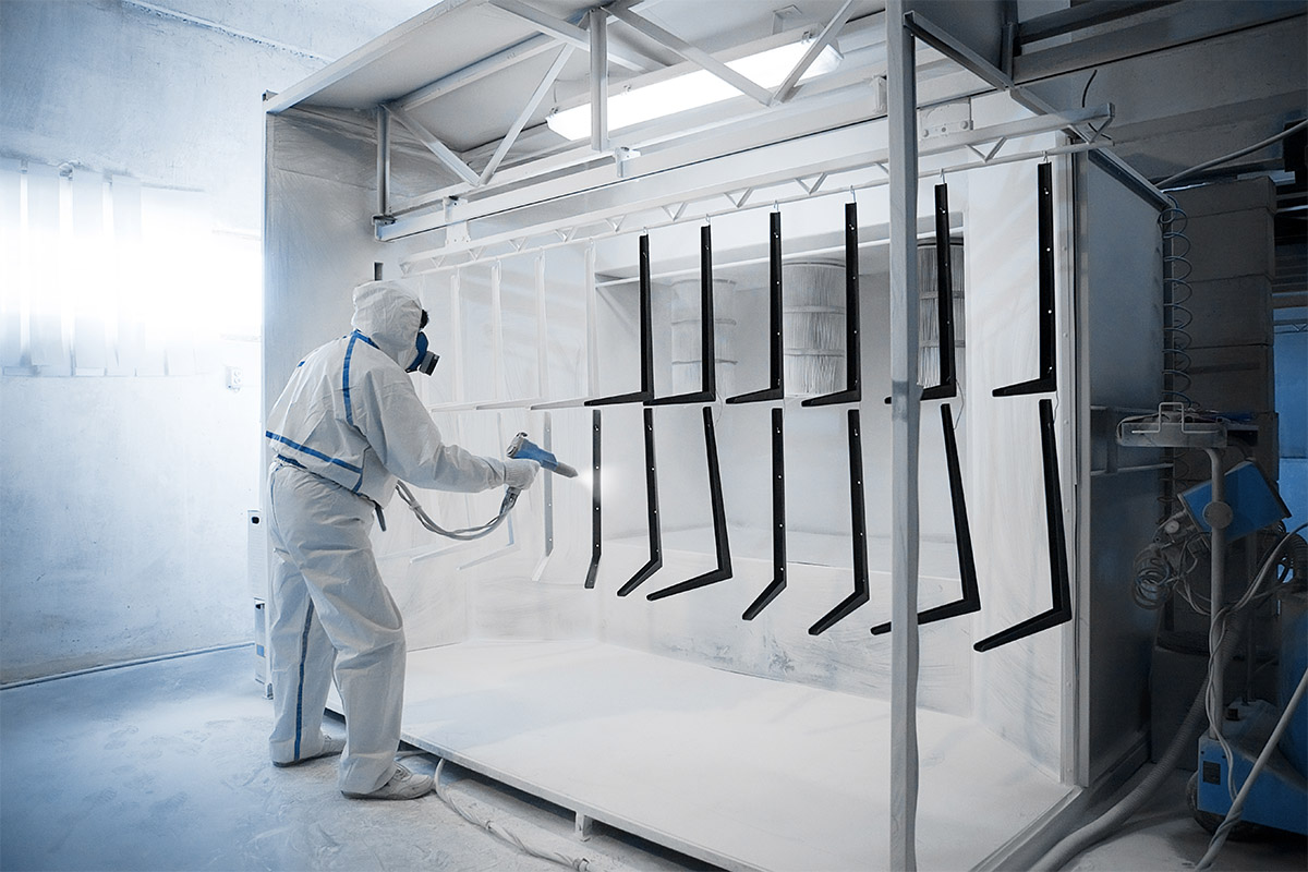 man applying powder coating in spray booth