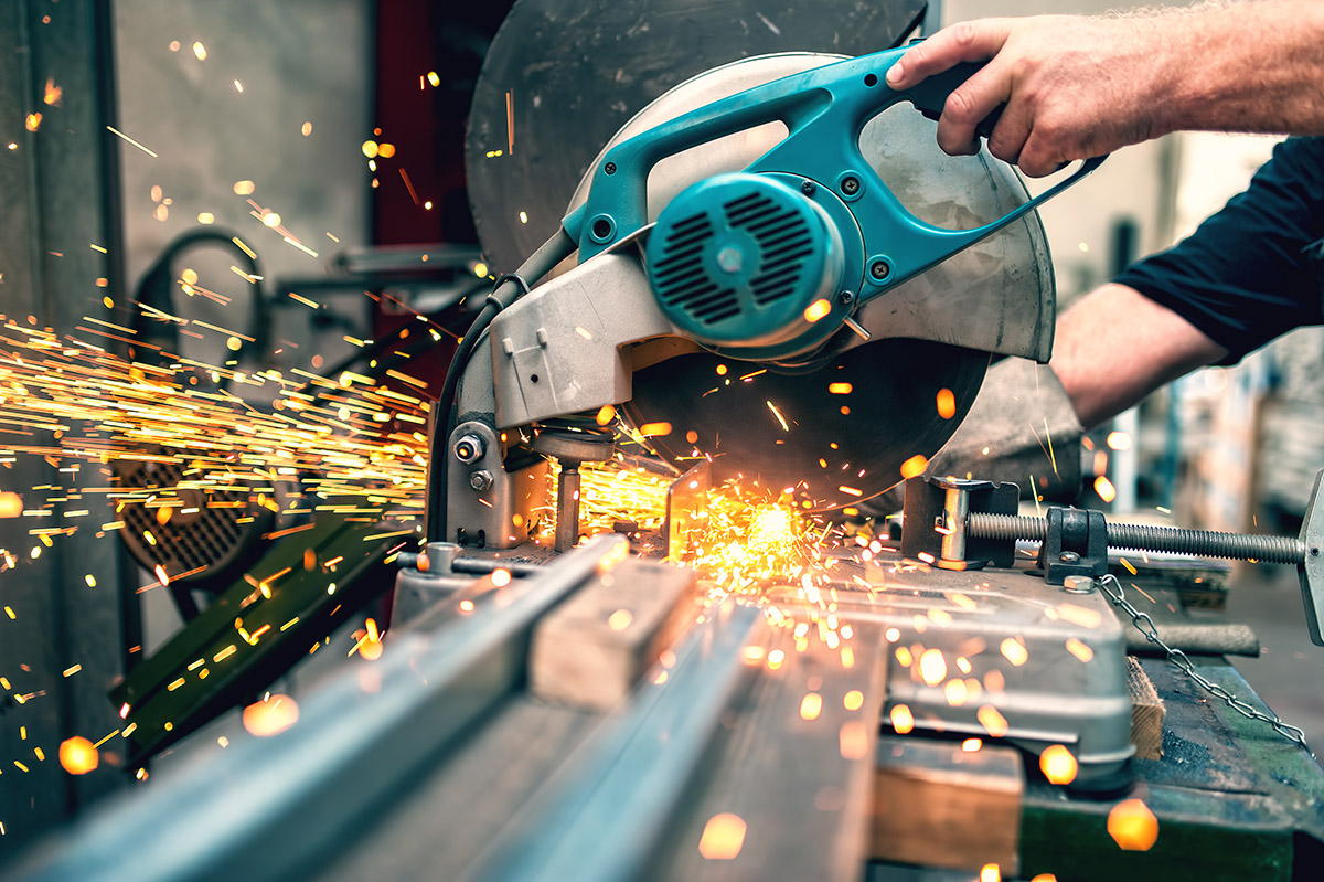 Indusrial Worker using a miter saw to cut metal